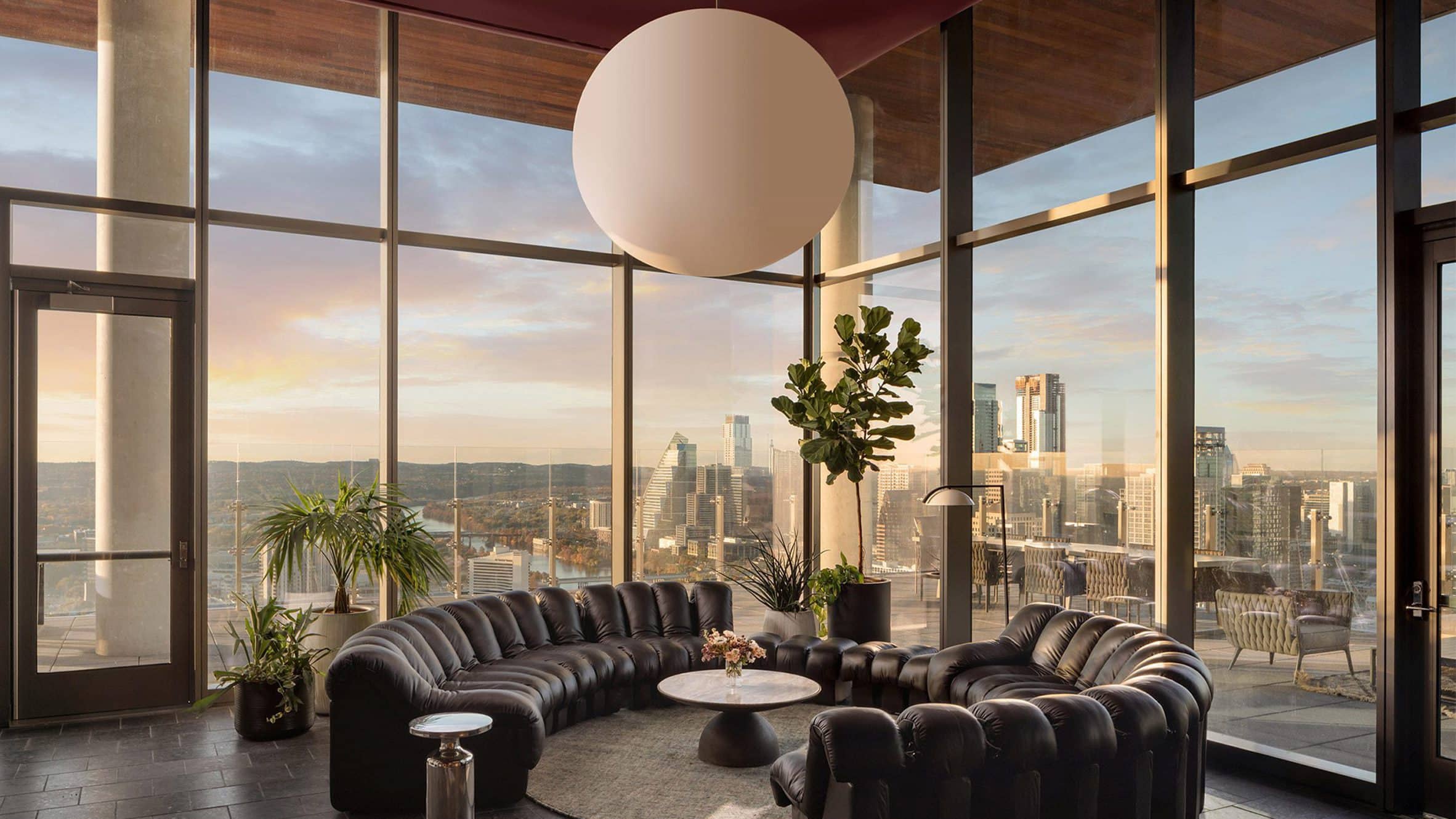 A residence interior with floor-to-ceiling glass looking out over the city at dusk.